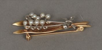 A 9 ct gold seed pearl mounted brooch Formed as a bow tied floral frond. 5 cms wide. Overall good,