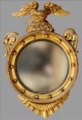 A Regency carved giltwood convex wall glass The ball mounted circular frame surmounted with an eagle