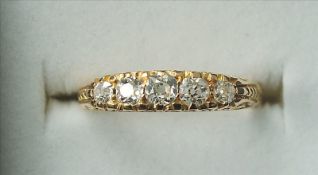 An 18 ct gold and diamond five stone ring The stone set above scroll cast shoulders, Chester