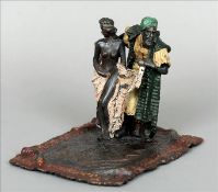 A cold painted bronze figural group Formed as a carpet seller unveiling a nude woman. 16 cms high.