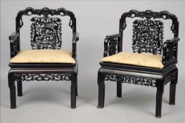 A set of four Chinese carved hardwood open armchairs The shaped carved top rail above the pierced