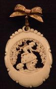 An ivory pendant Centrally carved with a pixie on a toadstool, suspended beneath an unmarked