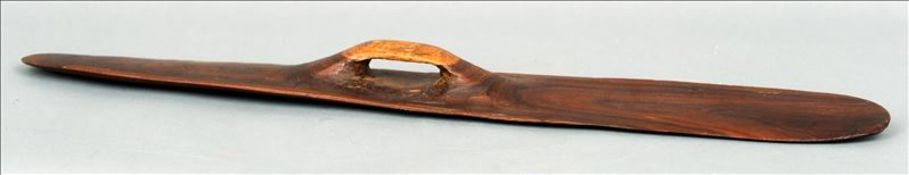 An Aboriginal parrying shield The slender hardwood body with a handle to one side, the other side