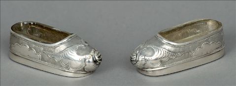 A pair of Chinese silver salts Each formed as a shoe with embossed decoration and clear glass