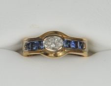 An 18 ct gold diamond and sapphire ring The centrally set oval diamond flanked by a band of six