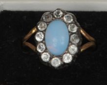 An 19th century unmarked yellow metal moonstone and paste set ring With central cabochon above