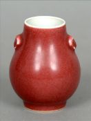 A small Chinese red ground vase With twin mask handles above the squat bulbous body, the base with