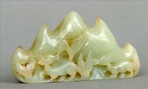 A small Chinese carved jade brush rest Formed as animal amongst foliage before mountains. 8 cms