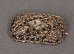 An unmarked diamond set brooch Of domed faceted rectangular shape with pierced decoration set with