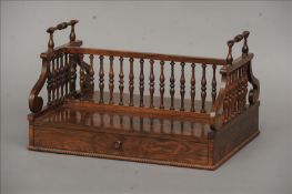 A 19th century rosewood book rack, in the manner of Gillows The twin turned carrying handles above