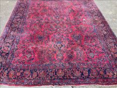 An early 20th century Persian wool carpet The wine red field extensively filled with scrolling vines