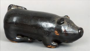 A 19th century treacle glaze pottery model of a pig Naturalistically modelled laying on all fours,