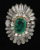 An Art Deco style platinum, diamond and emerald ring The central emerald bordered with a row of