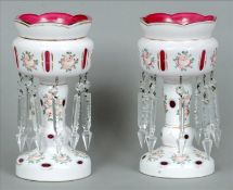 A pair of cranberry and white overlay glass table lustres Each painted with pink roses and hung with