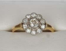 An 18 ct gold and diamond ring The plain band beneath the flowerhead setting, the central stone