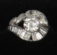 A platinum and diamond ring The central claw set diamond above a row of baguette cut diamonds, the