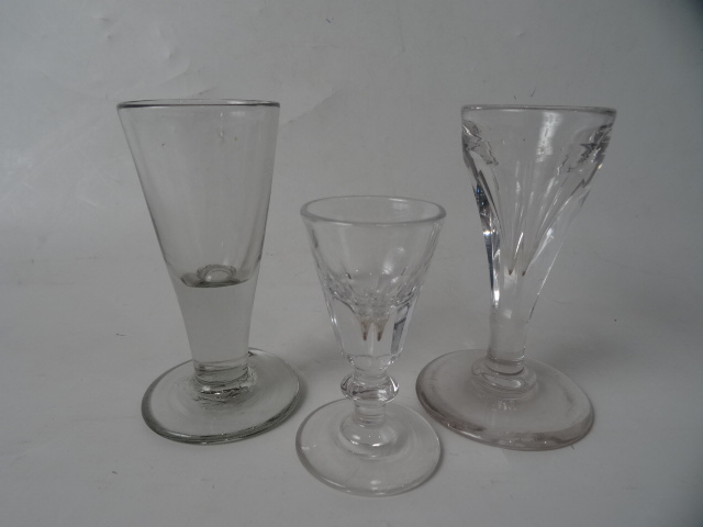 AN 18THC DECEPTIVE DRAWN FIRING DRAM GLASS with TWO DECEPTIVE FLUTED DRAM GLASSES.    10.5cm, 10.