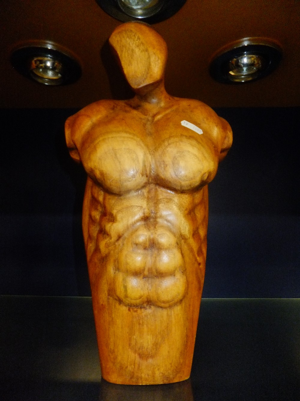 A carved wooden figure of a male torso