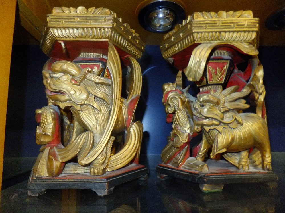 A pair of Oriental ornately carved gilt wood and painted stands