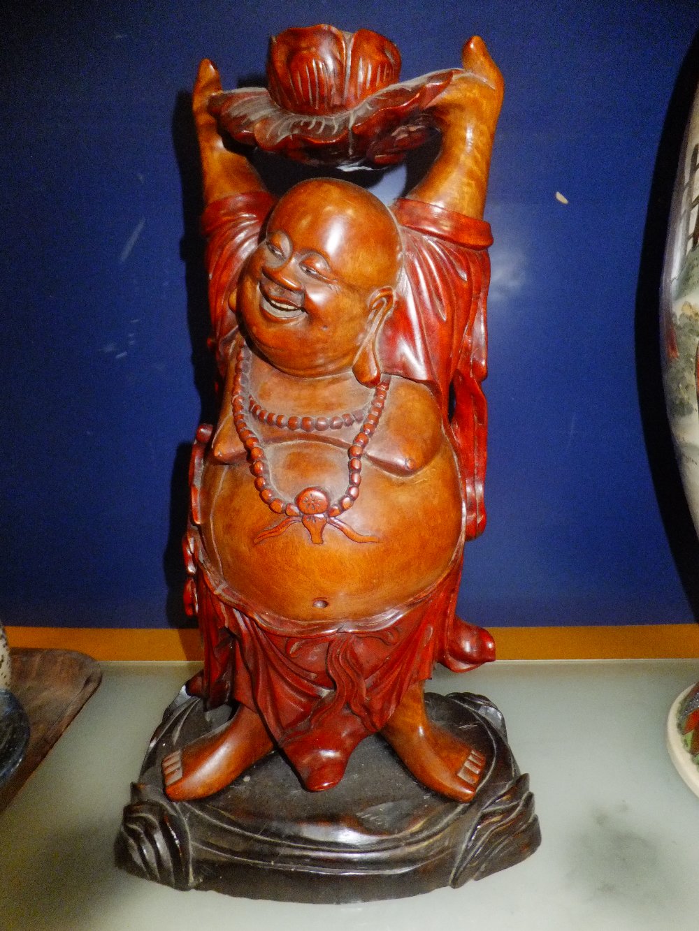 A carved wood figure of a Buddha holding lotus flower