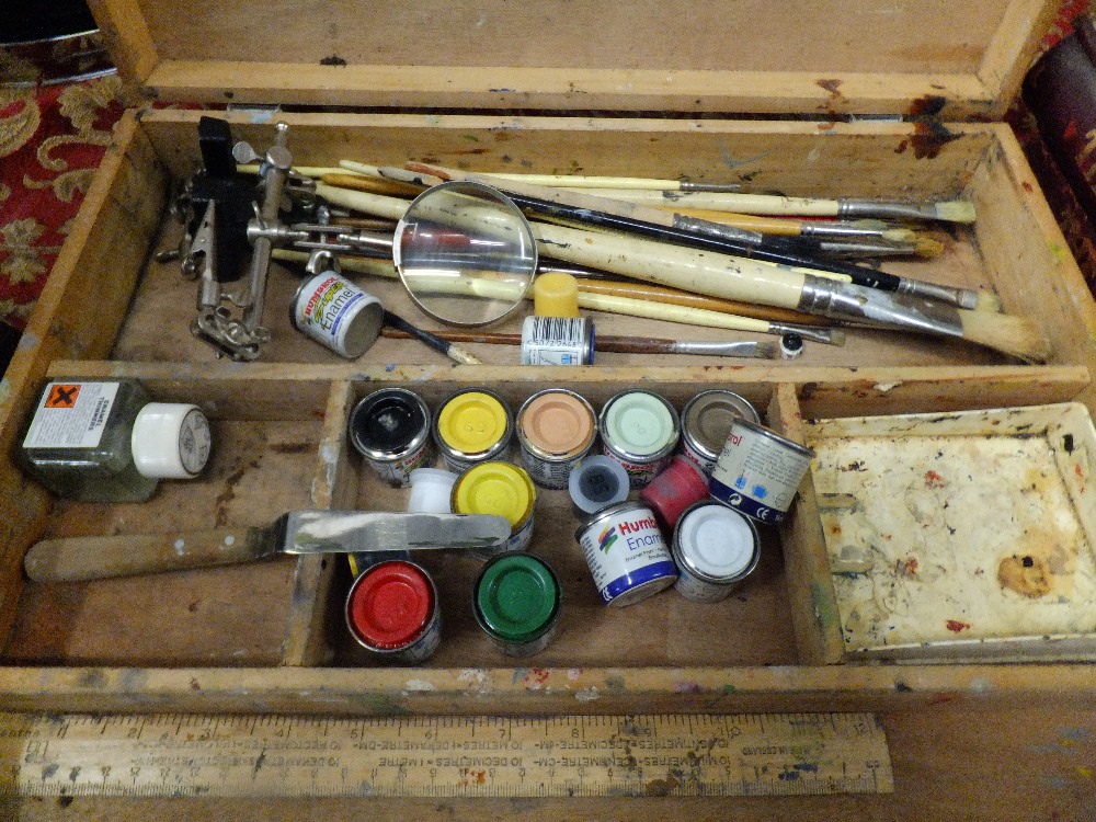 A vintage artists wooden case with a selection of enamels brushes and a magnifying glass etc