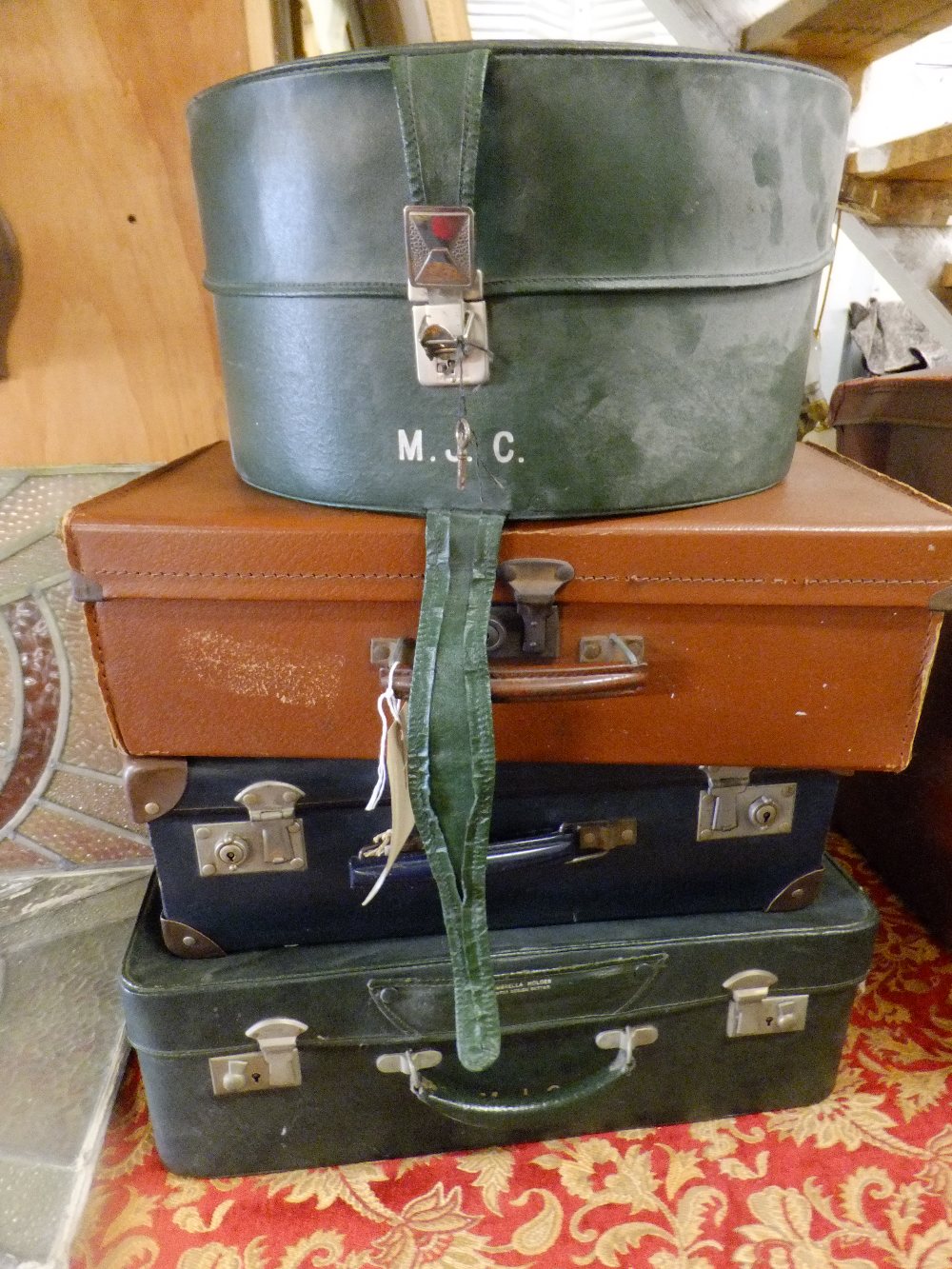 Three vintage leather suitcases and a green leather hat box with initials M.J.C to front