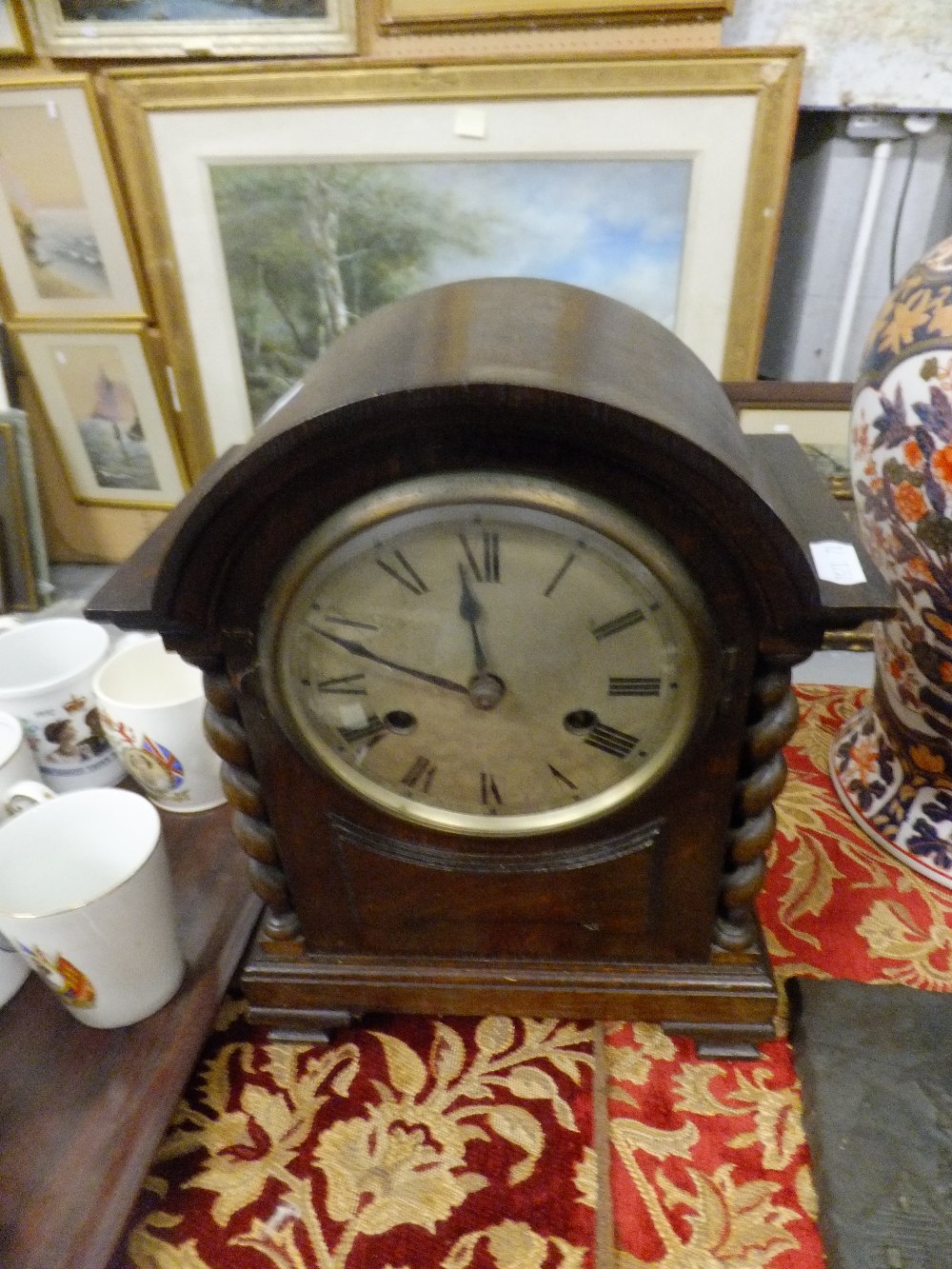 An oak-cased mantle clock with barley twist column detail and domed pediment