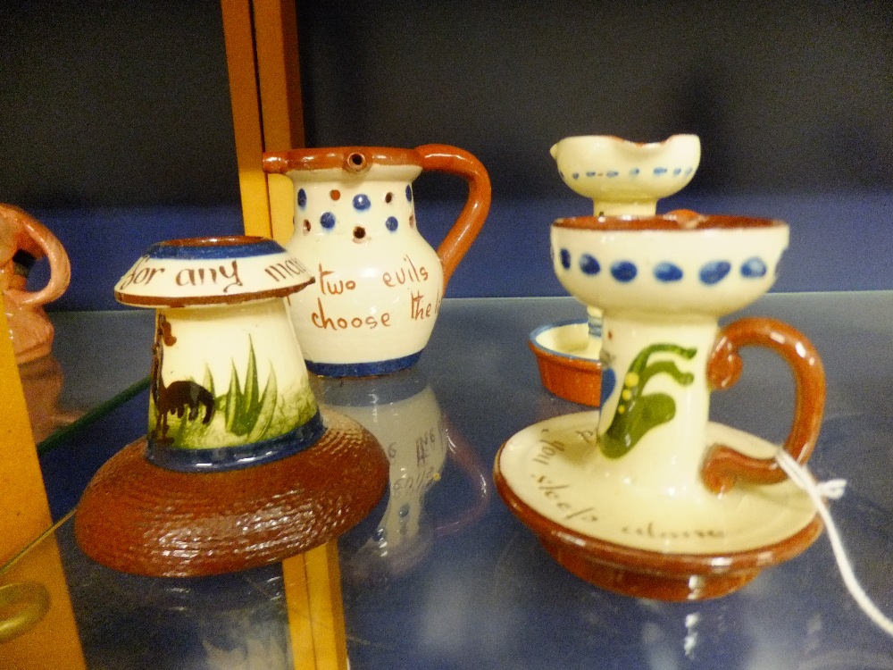 A selection of Torquay pottery motto-ware to include puzzle jug, candle holder etc