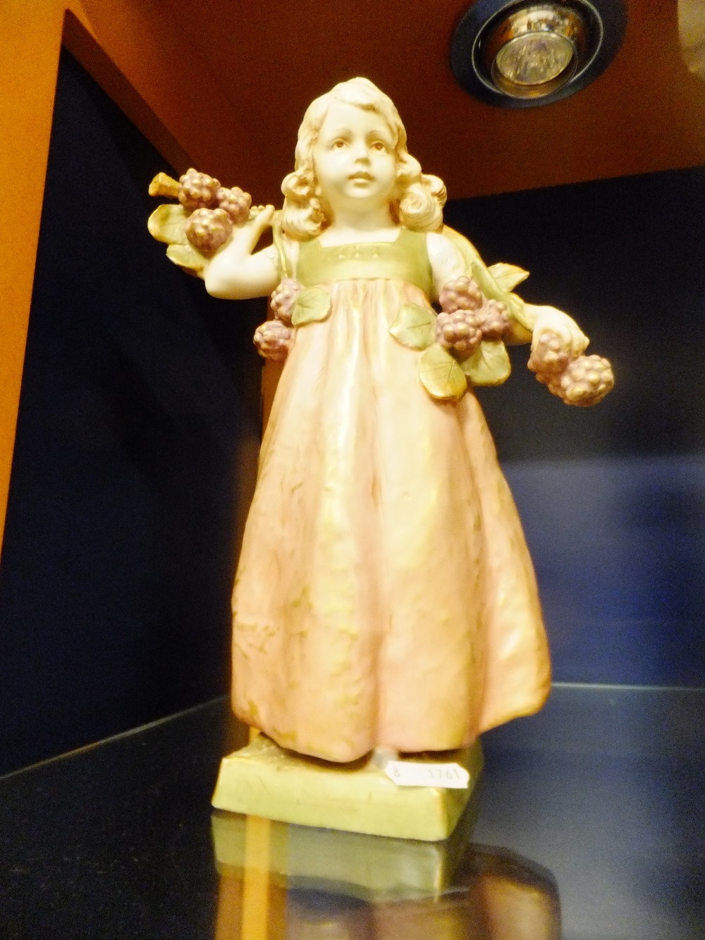 A Royal Dux figurine of a young girl carrying grapes, marks to base slightly A/F