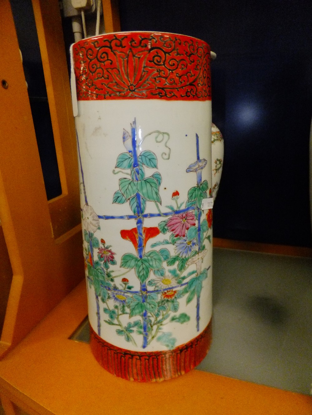 A large 19th C Chinese cane stand pot with hand painted decoration of flowers with scrolled boarders