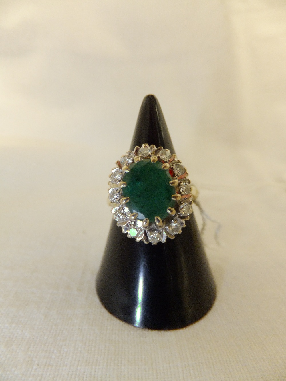 An 18ct gold ring having central emerald surrounded by diamonds, size K