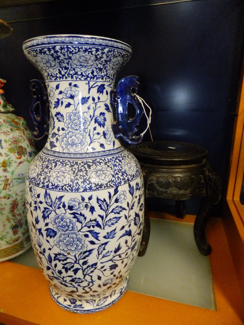 A Chinese blue and white vase having floral decoration, stylized handles and resting on a carved