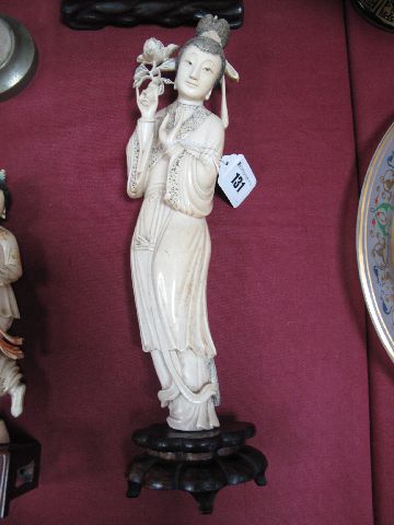 An Early XX Century Chinese One Piece Ivory Tusk Carving of Guanyin, standing, holding a flowering