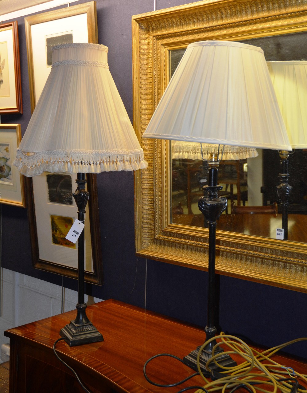 A pair of bronze effect column lamps, each mounted by urn finial, turned column, on graduated plinth