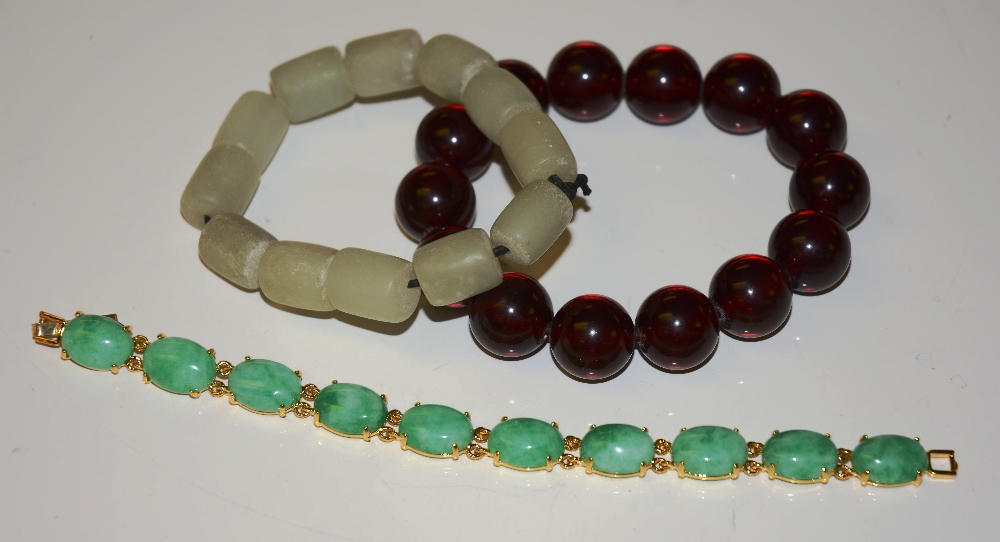 Two jadeite bracelets and a cranberry amber style bracelet (3)