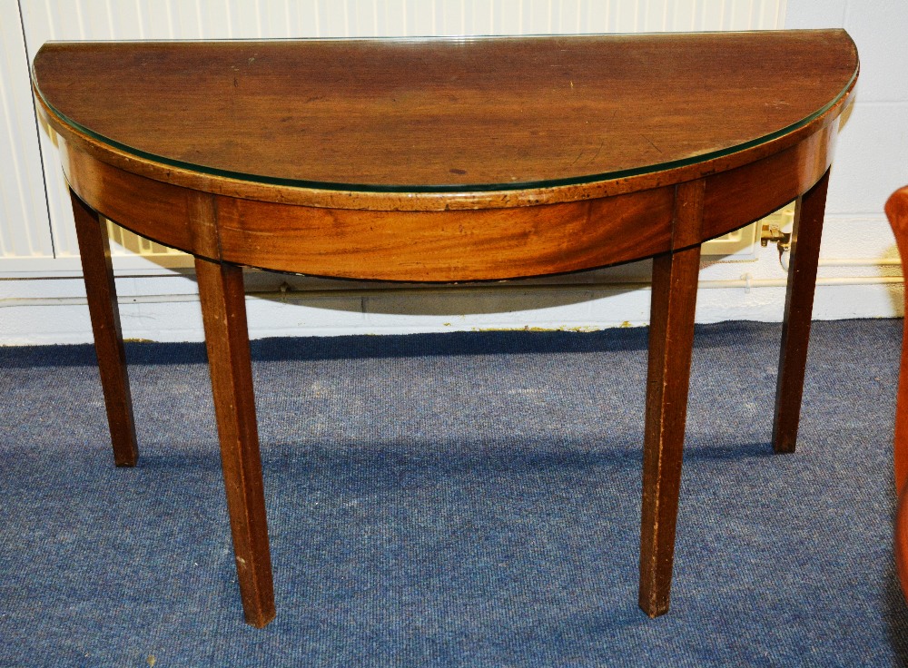 A late Georgian mahogany demi lune table, with ebony strung frieze raised on square tapering legs,