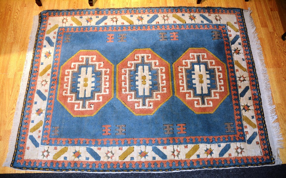 An Eastern rug with triple medallions over light blue ground and cream and pink border, 195 x 138cm