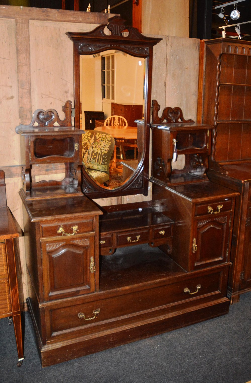 A mahogany dressing chest, the rectangular swing mirror with broken pediment, flanked by shelves and