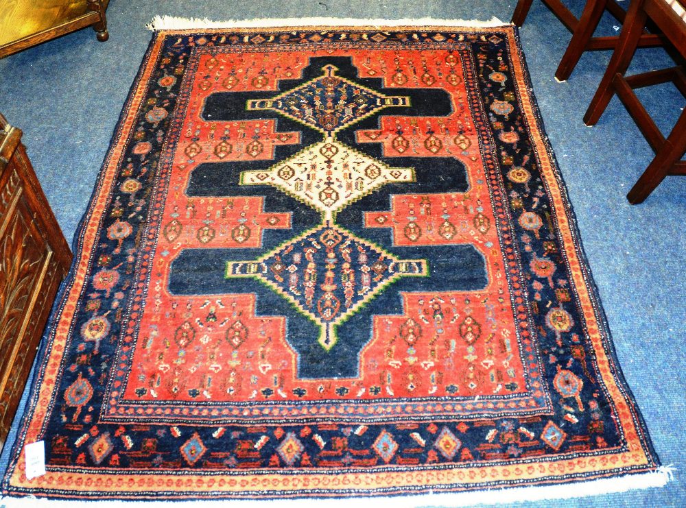 A Persian rug, with triple diamonds and blue cruciform over pink ground and blue borders, 173 x
