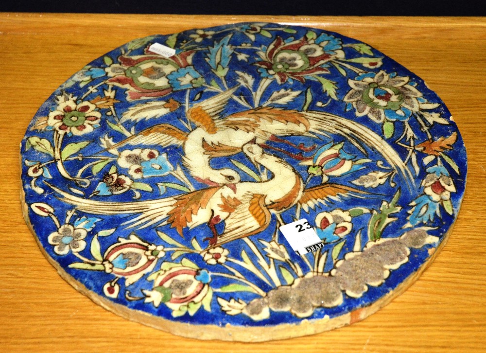 A 20th Century Iznik style ceramic round plaque, decorated with birds and foliage on a blue ground