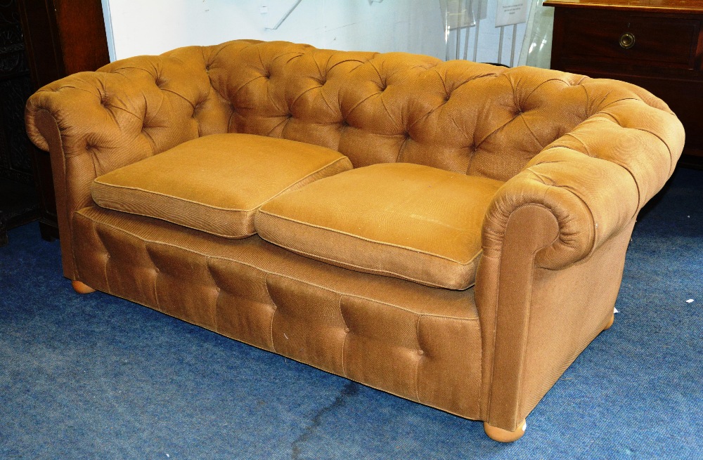 A button back Chesterfield sofa, with loose cushion seat raised on bun feet, 187cm wide x 68cm