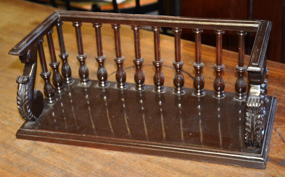 A brown painted desk book stand, with three quarter balustrade terminating in acanthus scrolls on