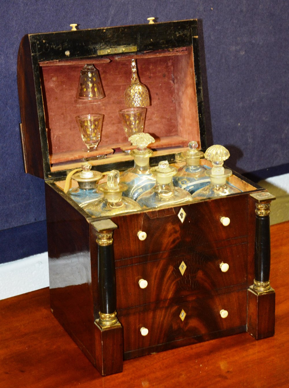 A 19th Century tantalus in the form of a roll top desk - the hinged top enclosing 6 decanters and