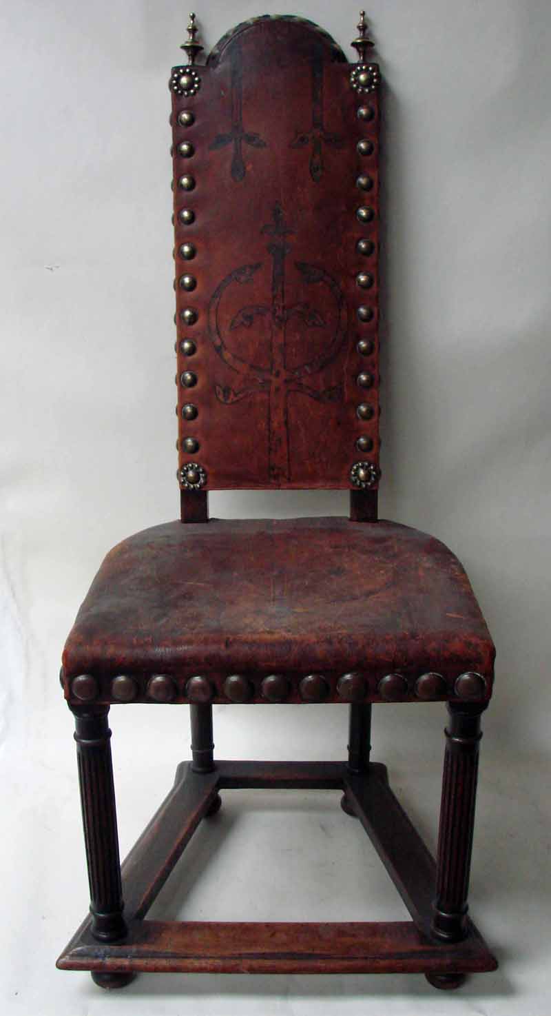 A 19th century Southern European oak frame hall chair, the arched top rail flanked by brass
