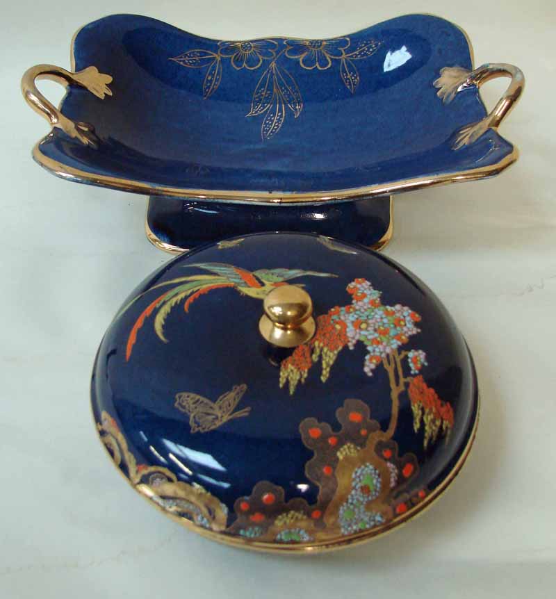 A Carlton ware lidded box of compressed circular form decorated in the Bird of Paradise design with