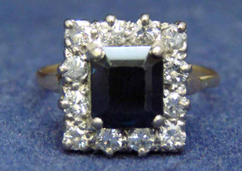 An 18ct gold (tested) sapphire and diamond cluster ring, the square emerald cut sapphire approx 2.