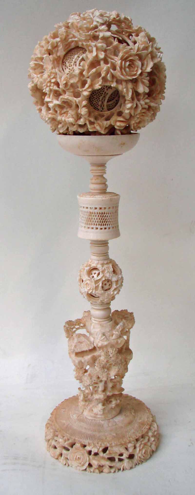 A Chinese early 20th century carved ivory Puzzle Ball on stand, the outer layer openwork carved with