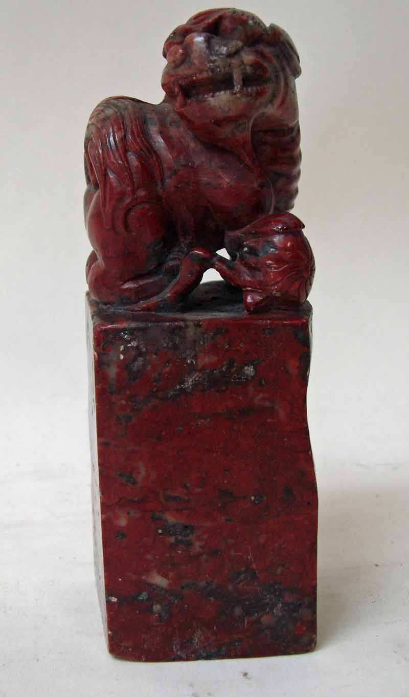 A Chinese Qing Dynasty chicken blood soapstone Seal, the upper portion carved with a lion dog,