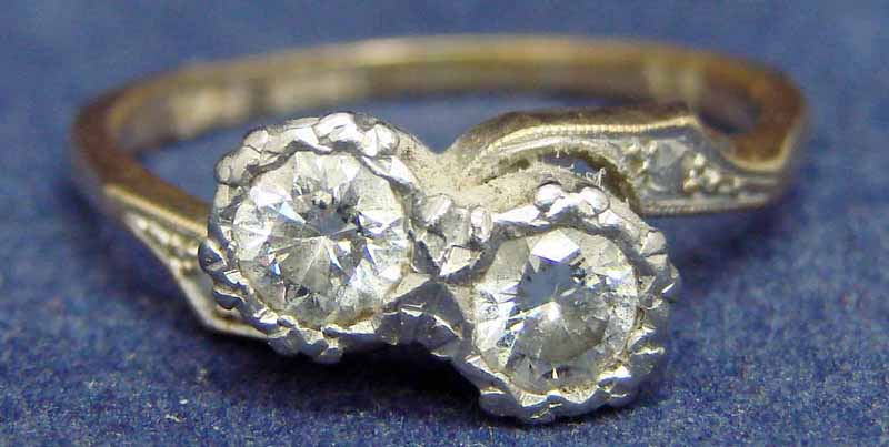 An 18ct gold and platinum ladies two stone crossover diamond ring, each stone approx 0.25ct, size N
