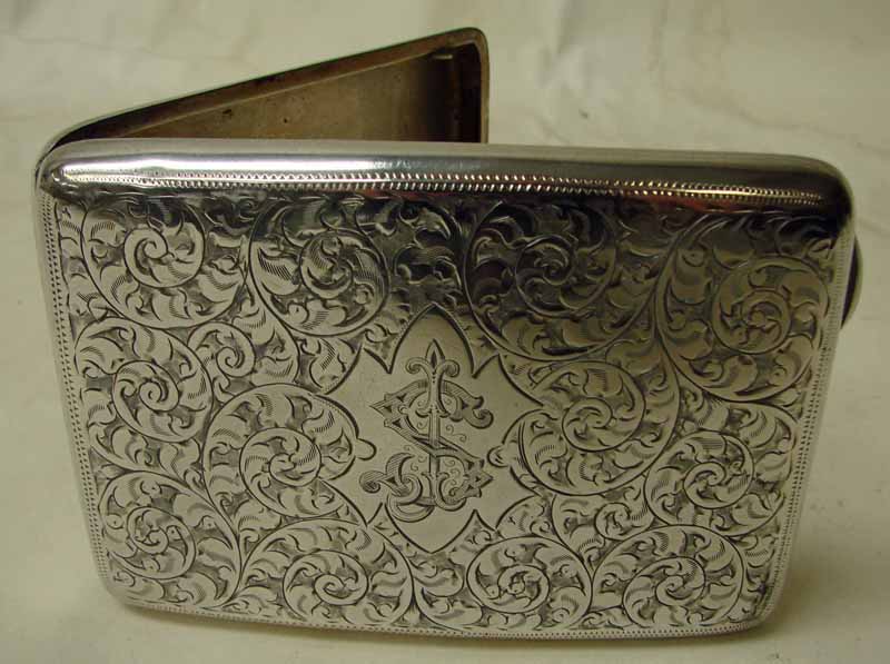 An early 20th century silver cigarette case of arched rectangular form, foliate engraved to both